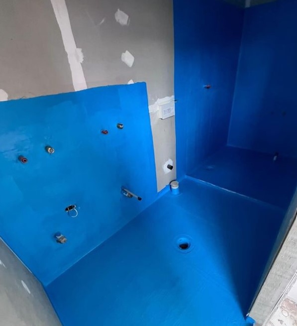 Vibrant blue bathroom in progress with glossy finish and incomplete wall.