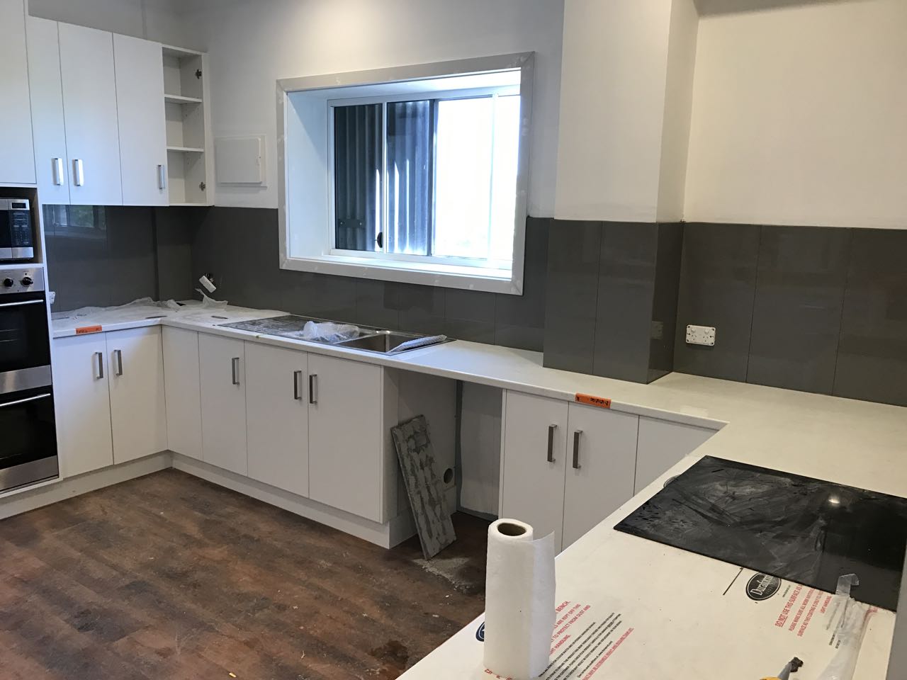 Contemporary kitchen renovation in progress with white cabinets and a gray tile backsplash