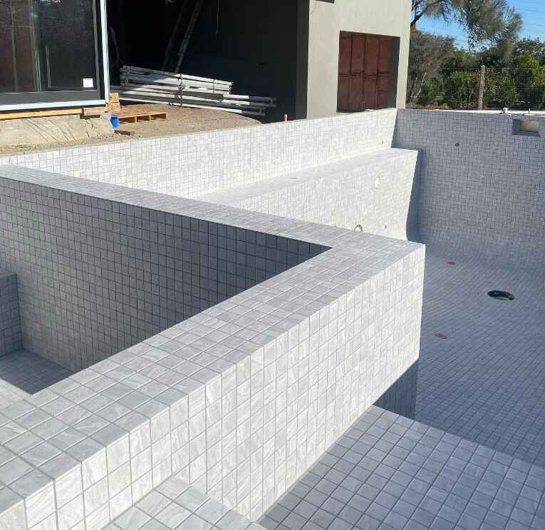 Custom swimming pool building with a sophisticated tiled finish and rectangular design.