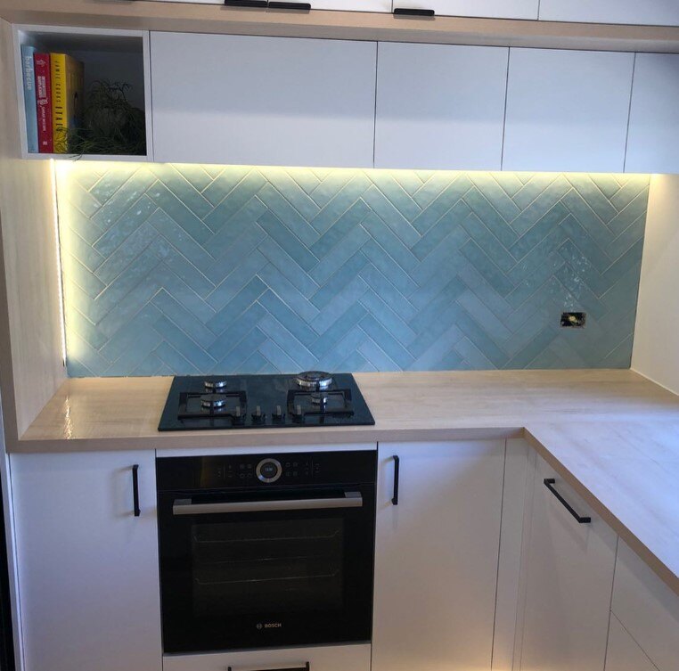 Contemporary kitchen with blue-tiled backsplash, gas cooktop, and built-in oven.