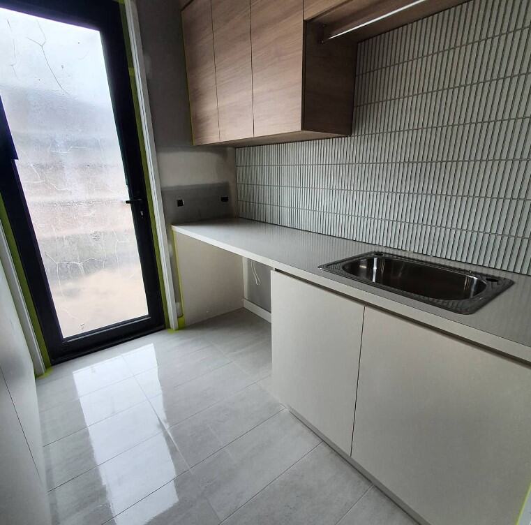 Sleek, modern kitchen with minimalist design, natural lighting, and streamlined white cabinetry.