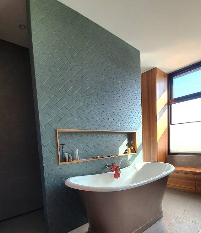 Luxurious minimalist bathroom with sleek bathtub and stylish herringbone tiles.