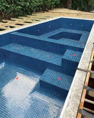 Blue tiled swimming pool under construction with clear water and visible steps